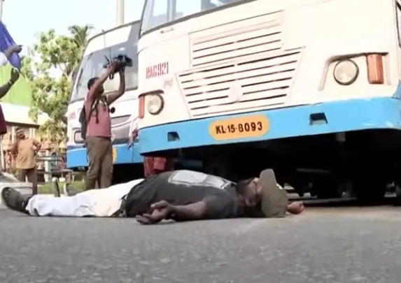പ്രതീകാത്മകചിത്രം | ബസിന് മുന്നിൽകിടന്ന് പ്രതിഷേധിക്കുന്ന ഹർത്താൽ അനുകൂലികളിലൊരാൾ | Image courtesy: Mathrubhumi News screengrab