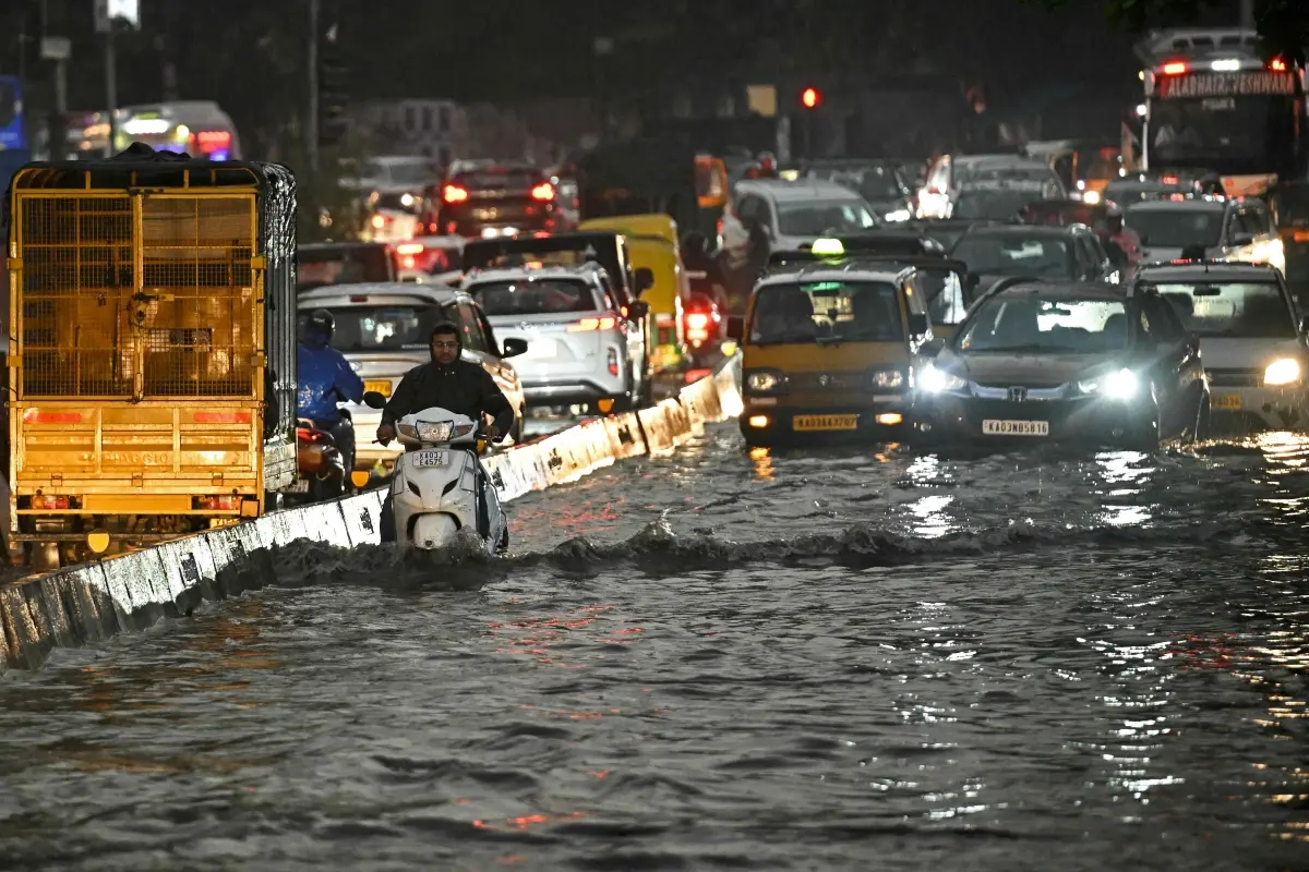 Commuters wade through a flooded street during rainfall in Bengaluru on April 29, 2026
