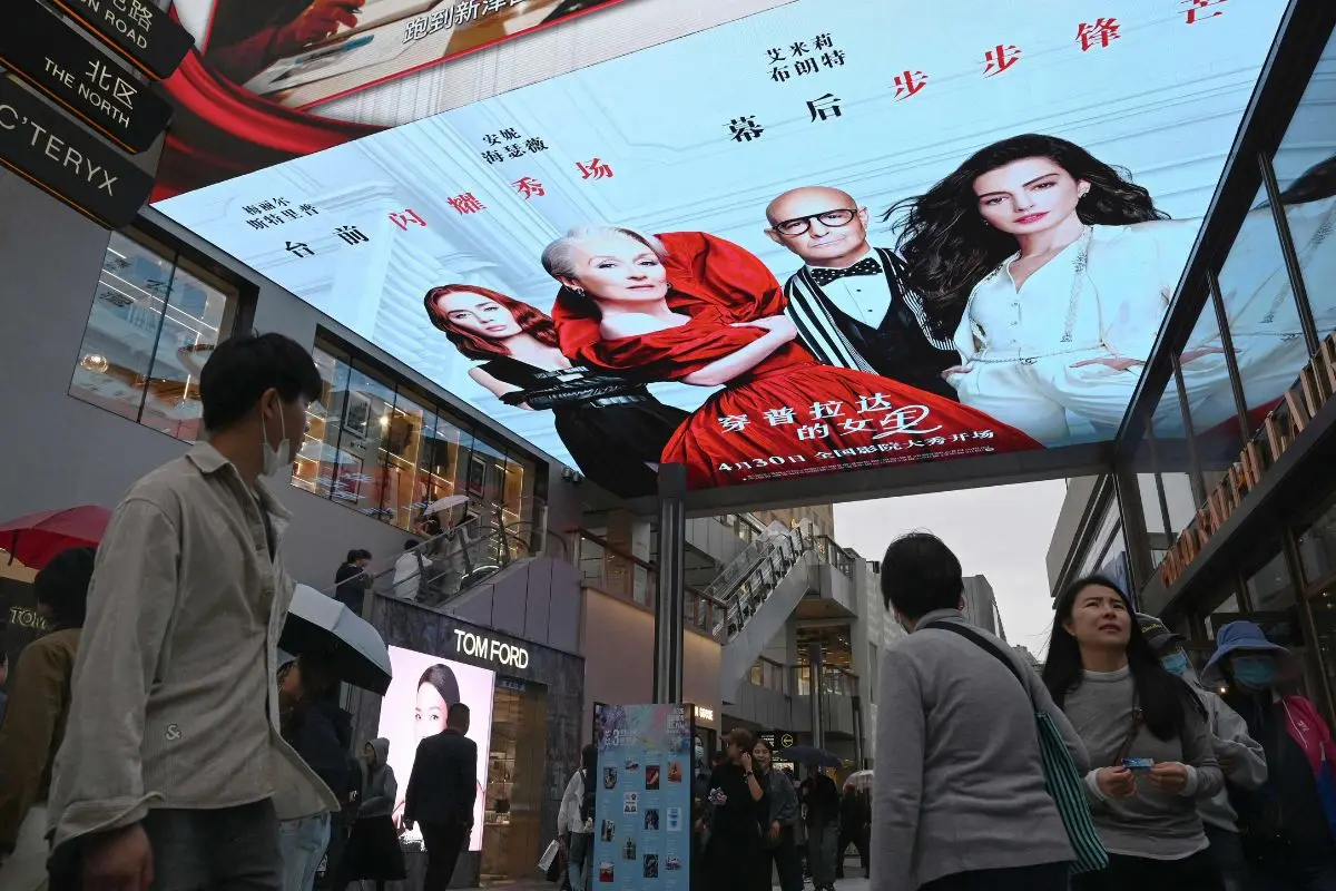People walk below an electronic billboard advertising the movie "The Devil Wears Prada 2" at a shopping mall in Beijing on May 2, 2026 (Photo: AP)