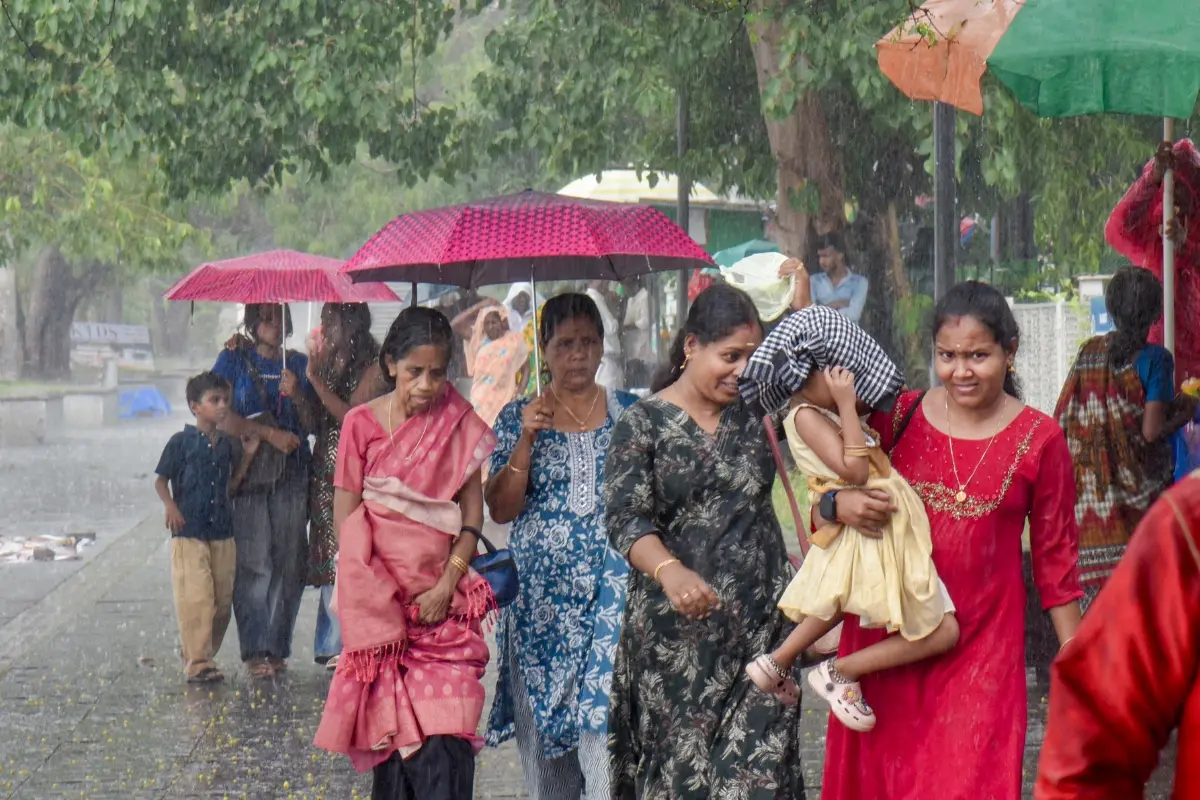 Women cover themselves while walking amid rainfall, in Kochi, Kerala.| Photo: PTI