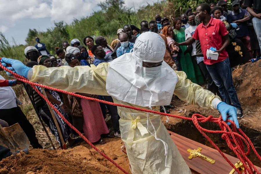 Red Cross workers prepare a coffin containing the body of a Ebola victim for burial at the Rwampara Cemetery