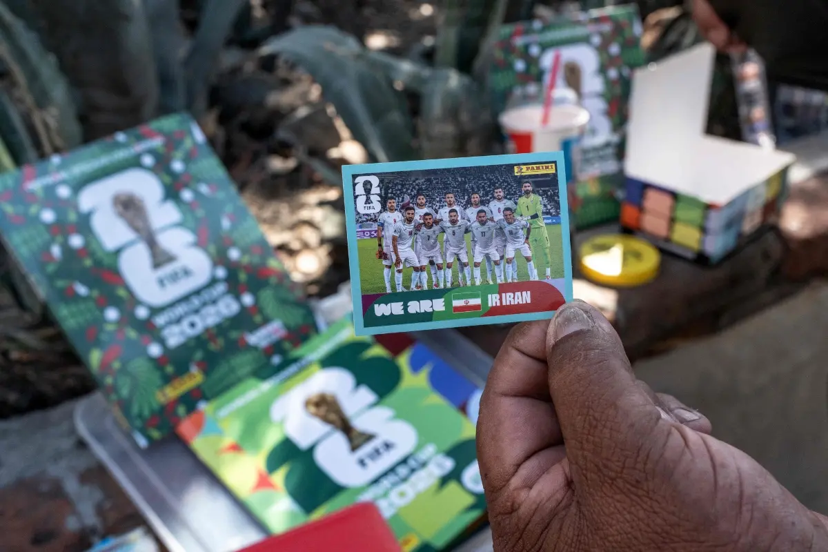A vendor shows a Panini sticker featuring the Iran national football team for the World Cup in Tijuana, Baja California state, Mexico | Photo: AFP