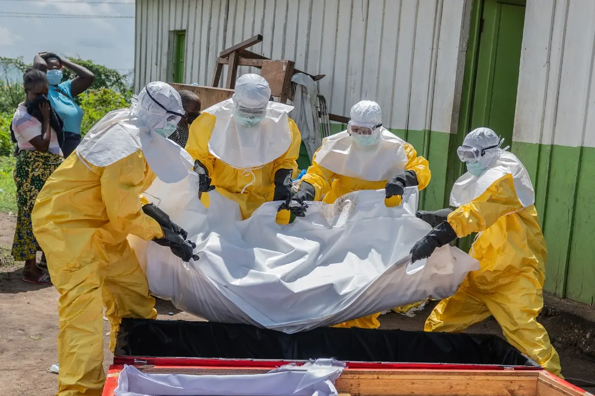 Red Cross workers carry the body of a person who died of Ebola into a coffin at a health center in Rwampara, Congo | Photo: AP