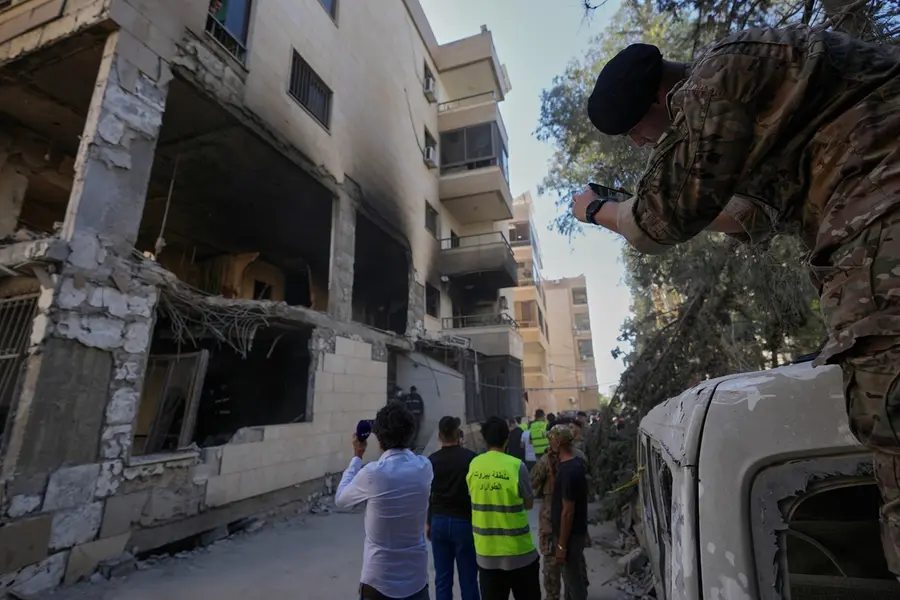 A Lebanese soldier takes pictures by his phone for a destroyed apartment that was hit in an Israeli airstrike in Choueifat town, southern Beirut, Lebanon