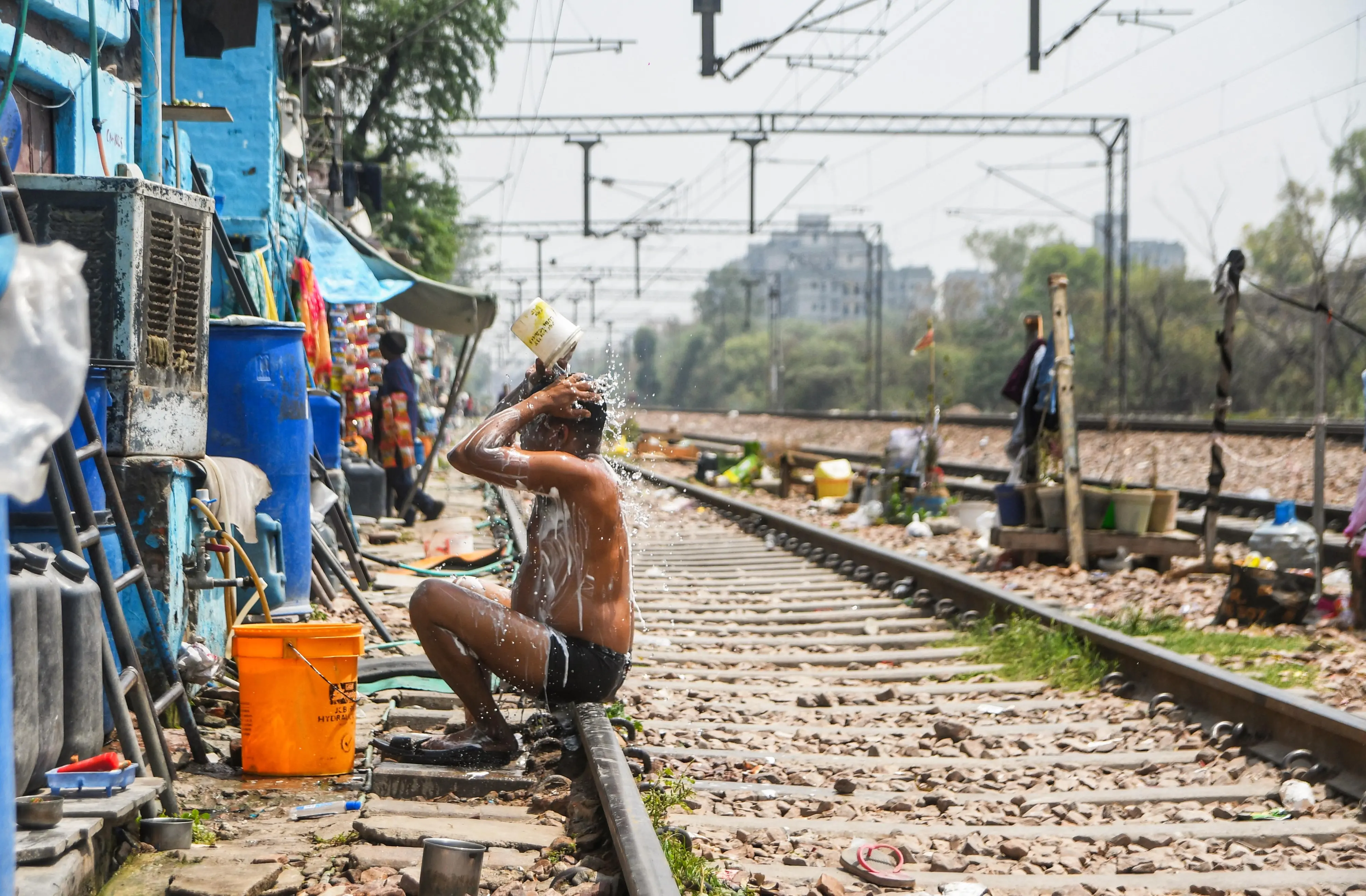 A man takes a bath next to the railway tracks, seeking quick relief from the severe ongoing heatwave at Mayapuri in New Delhi | ANI