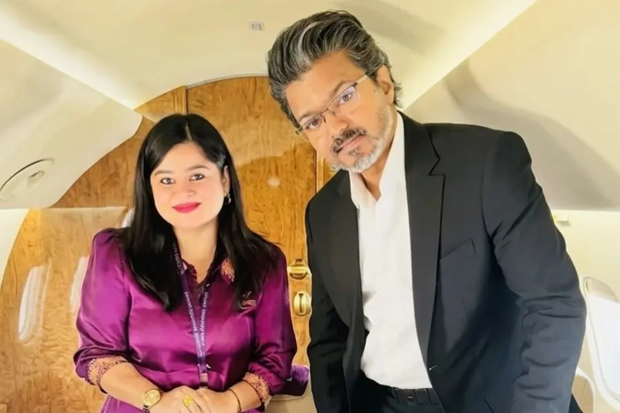 A cabin crew member smiling while posing for a photograph next to Tamil Nadu Chief Minister C Joseph Vijay inside an aircraft
