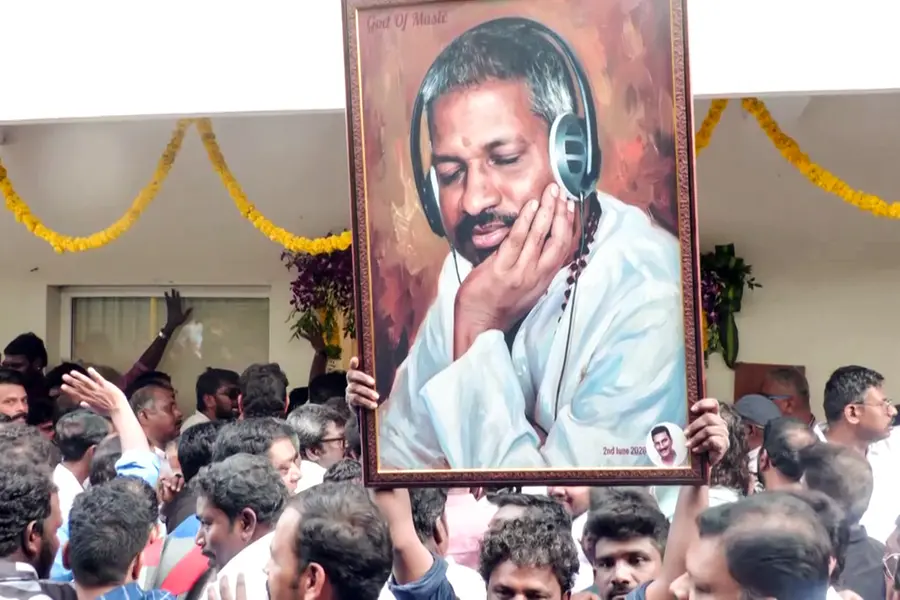 A fan holds the portrait of music composer Ilaiyaraaja on his birthday outside his Kodambakkam office
