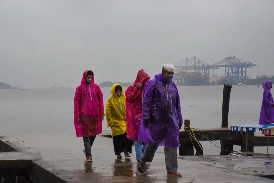 People cover themselves during rainfall as monsoon arrives at Marine Drive in Kochi