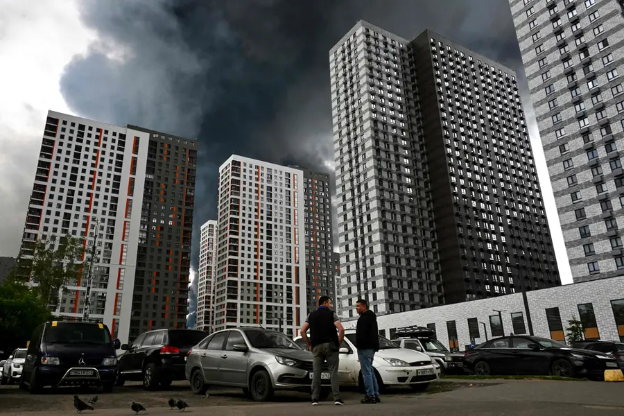 Men interact in a residential locality blanketed in black smoke in Moscow