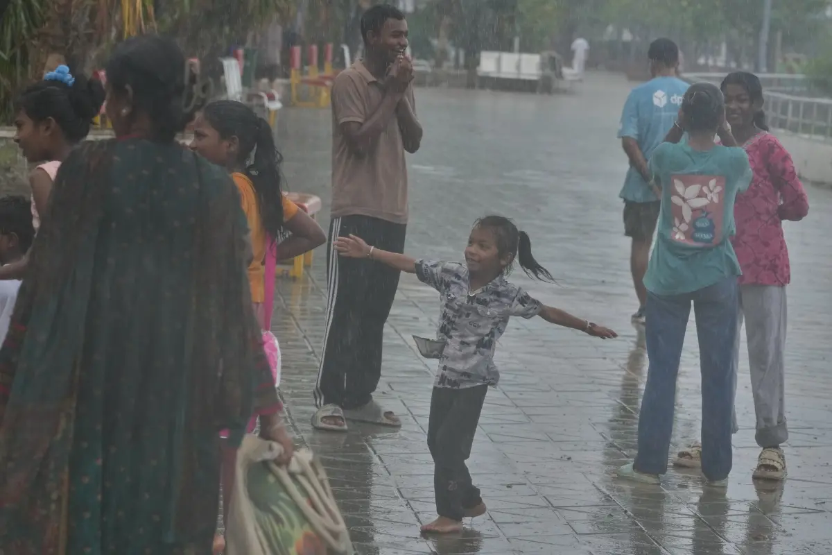 A girl, along with others, reacts in a monsoon shower in Mumbai, India.| Photo: AP
