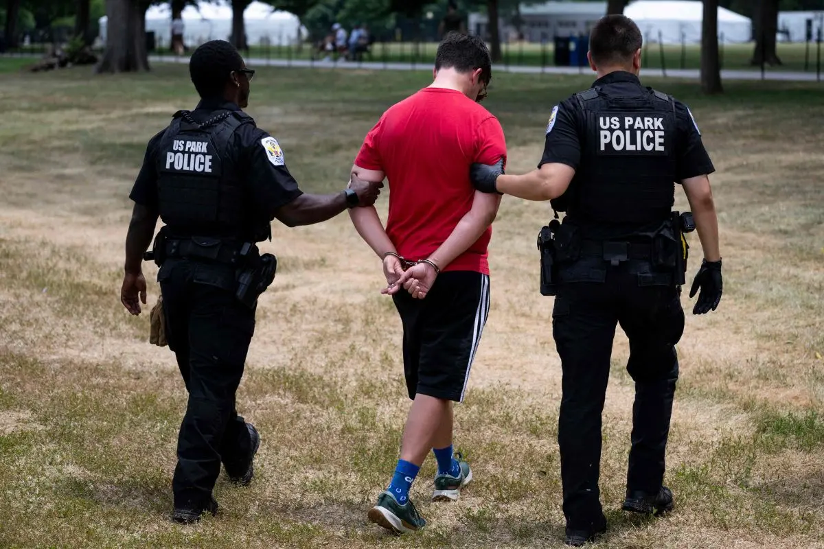 A man is escorted away by US Park Police Officers after being placed under arrest for disorderly conduct for allegedly shouting at Oklahoma State Troopers at the Lincoln Memorial Reflecting Pool following the completion of recent renovations in Washington, DC, on June 22, 2026 (Photo: AP)
