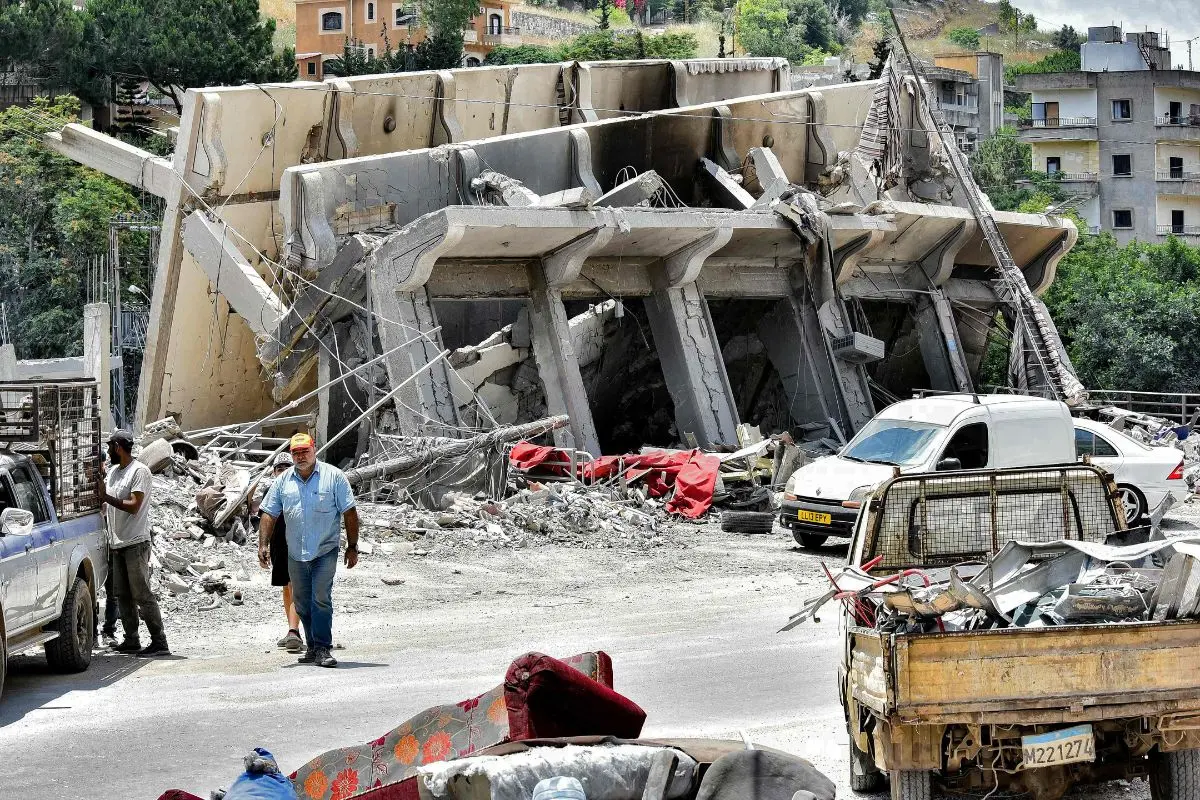 People walk past a collapsed building in the town of Nabatieh al-Fawqa in southern Lebanon on June 23, 2026 (Photo: AFP)