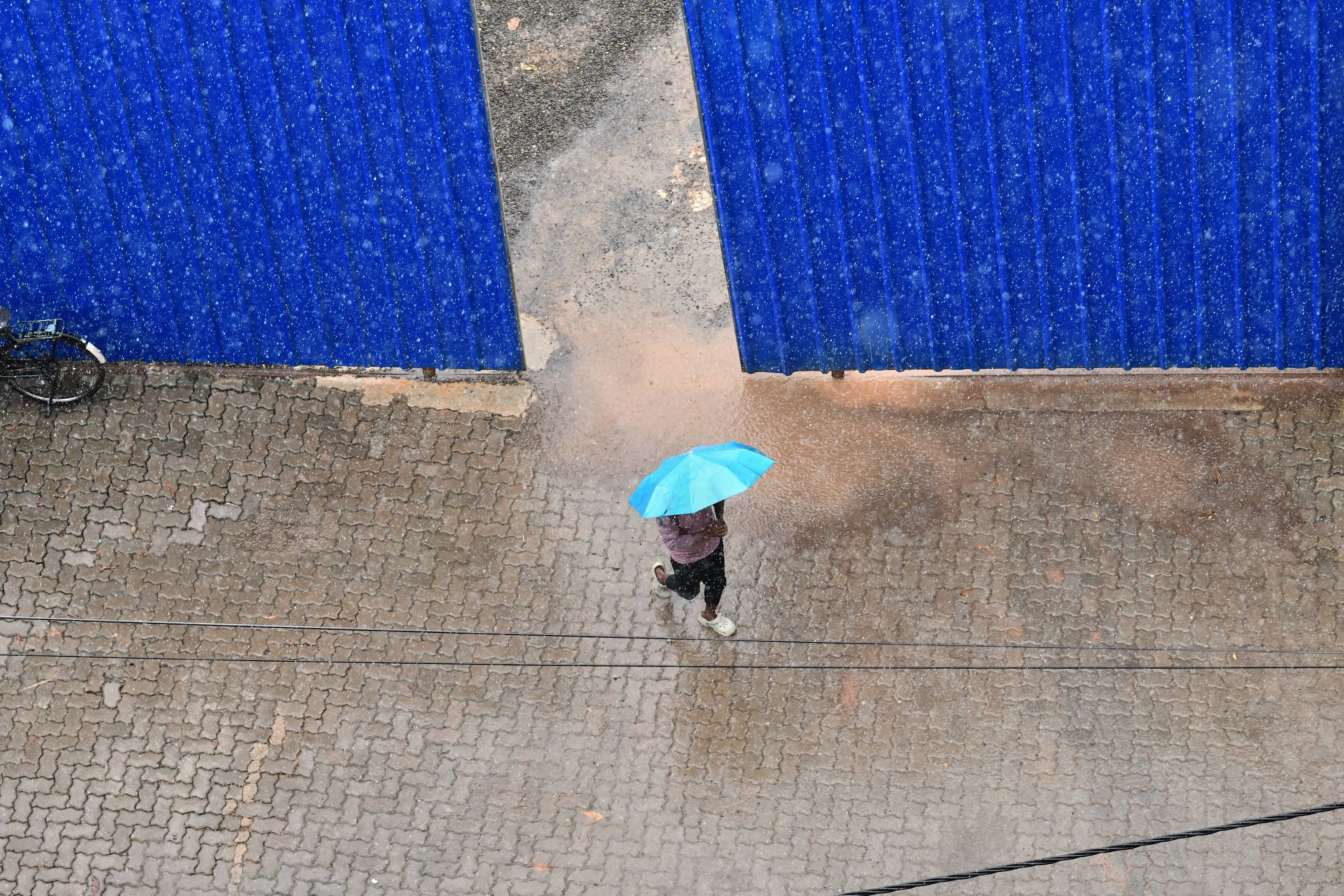 A man walks past a construction site holding an umbrella under heavy rain in Kochi, southern Kerala state, India.| Photo: AP
