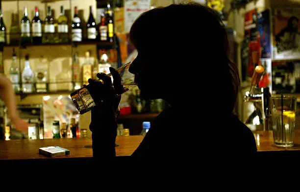 A woman enjoys a drink at a bar | Image: Uriel Sinai/Getty Images