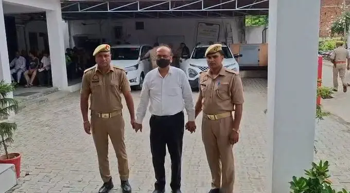 Shahjahanpur Assistant Municipal Commissioner Raj Kumar Gupta, arrested in connection with the alleged Rs 101 crore Sambhal government land scam, is escorted by Uttar Pradesh Police after his arrest.