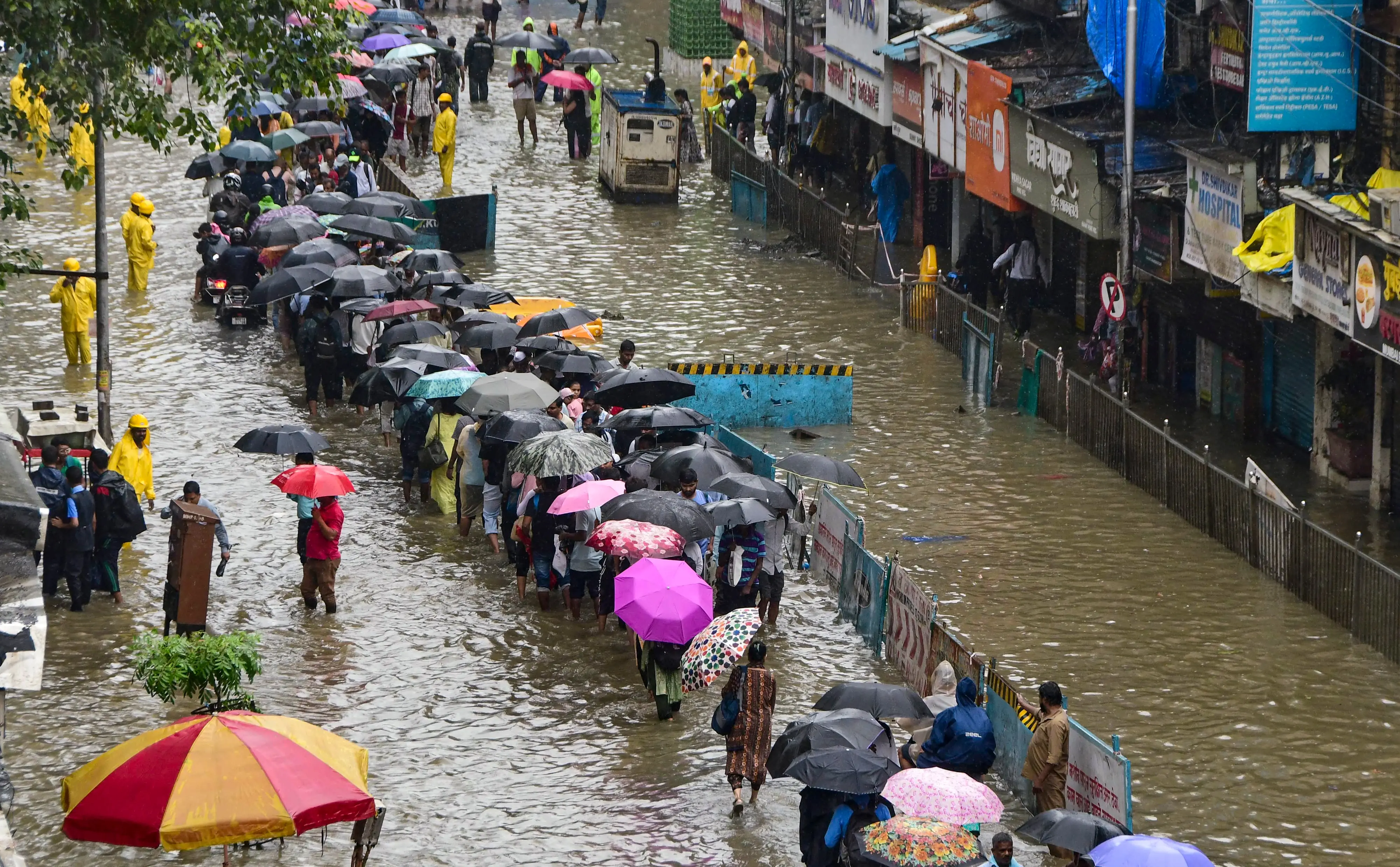Commuters carrying umbrellas make their way through a waterlogged street amid rainfall at Parel, in Mumbai