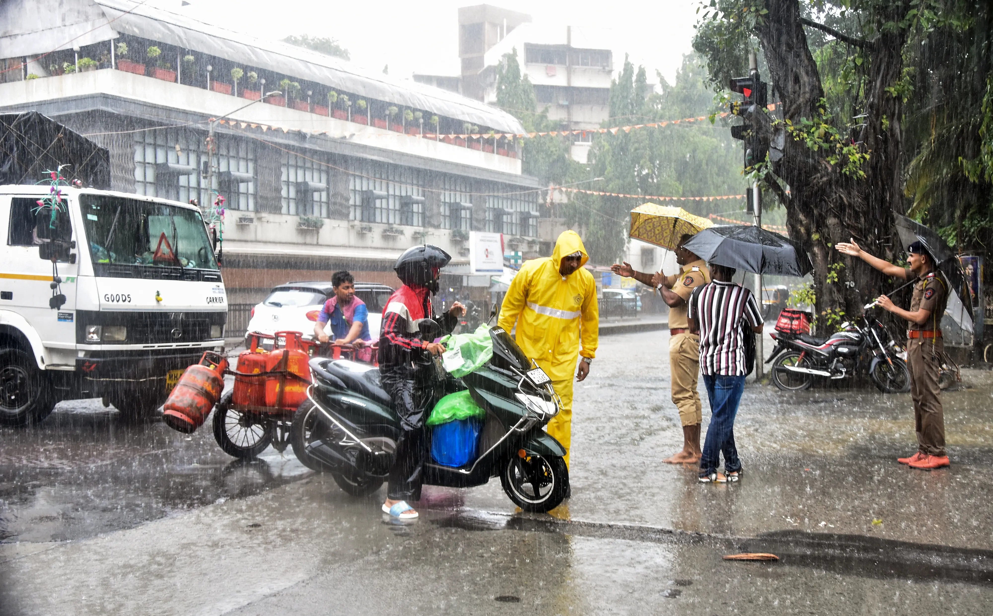 Vehicles ply on a rain-soaked road amid heavy rainfall