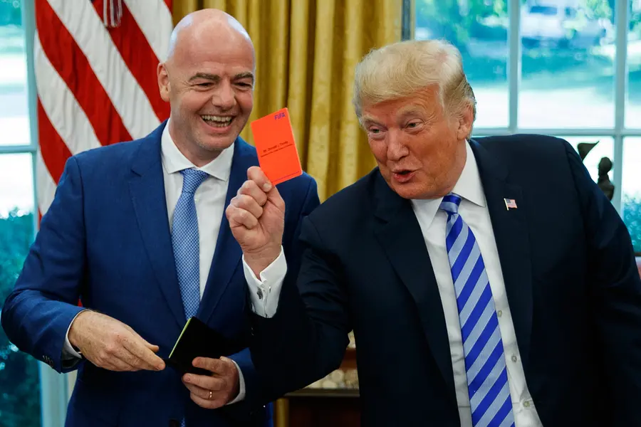 President Donald Trump holds up a red card during a meeting with FIFA president Gianni Infantino in the Oval Office