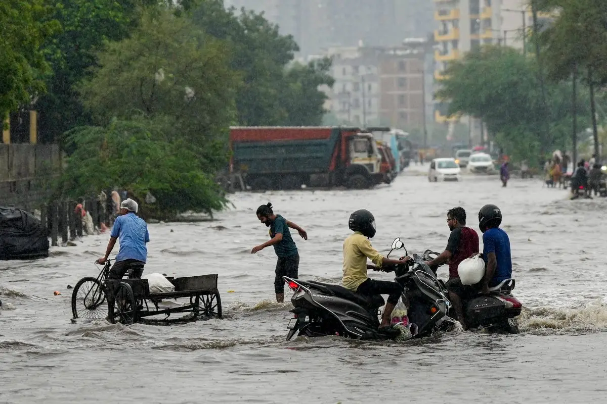 Commuters make their way through a waterlogged road following heavy rain, in the Gazipur area of New Delhi, on Thursday morning, July 9, 2026. (PTI Photo/Salman Ali)