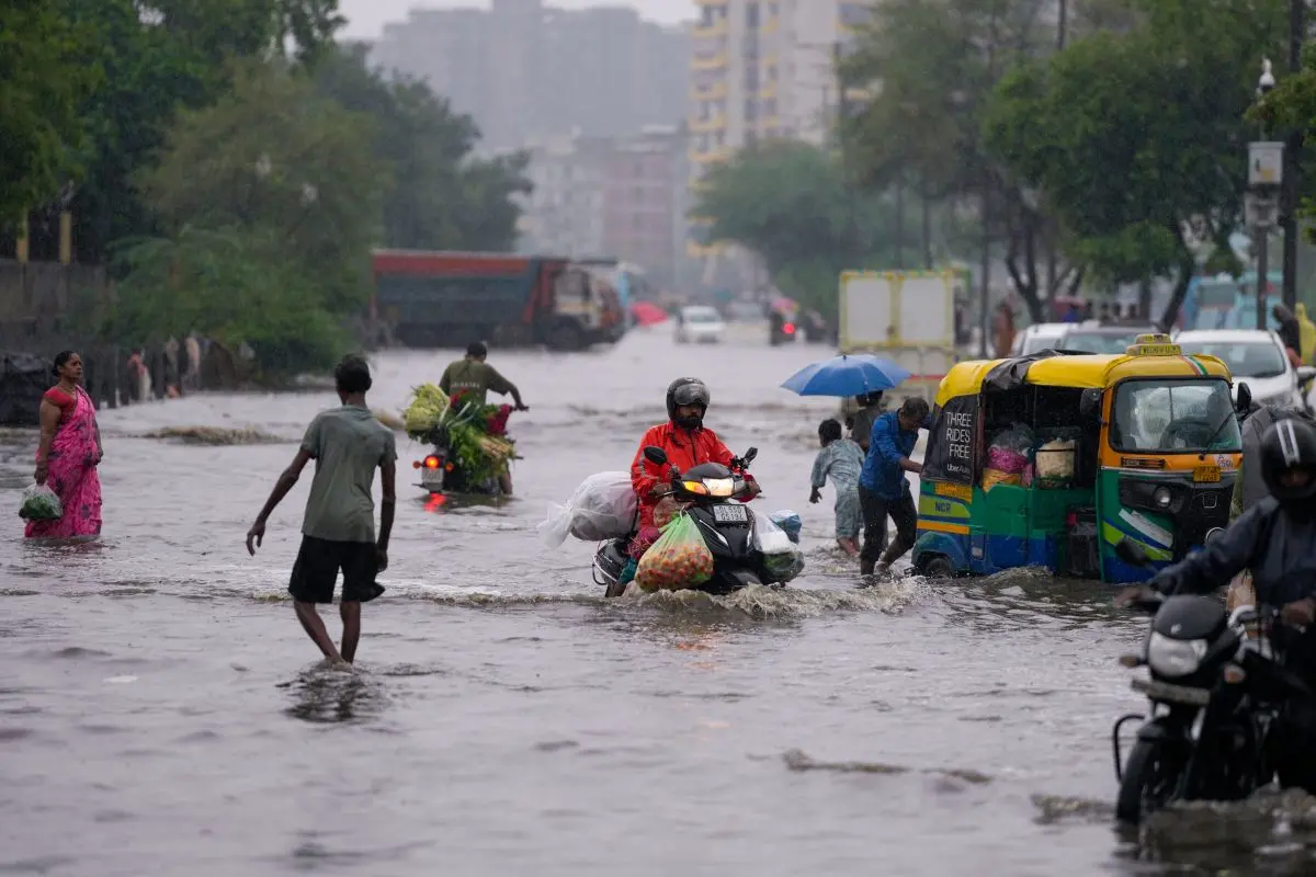 People make their way through a waterlogged road following heavy rain, in the Gazipur area of New Delhi (Photo: PTI)