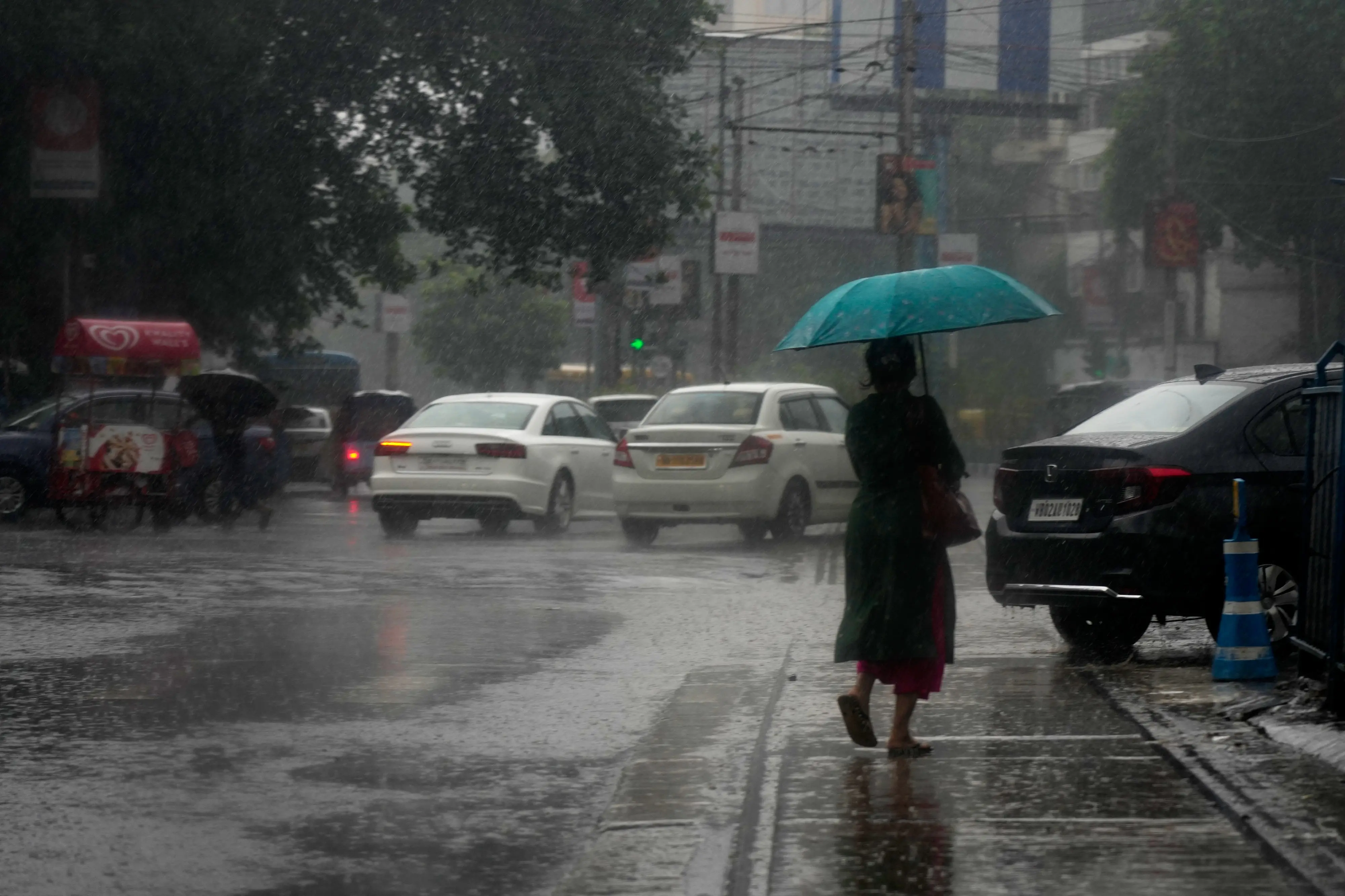A commuter crosses a street during heavy monsoon rain, in Kolkata, India.| Photo: AP