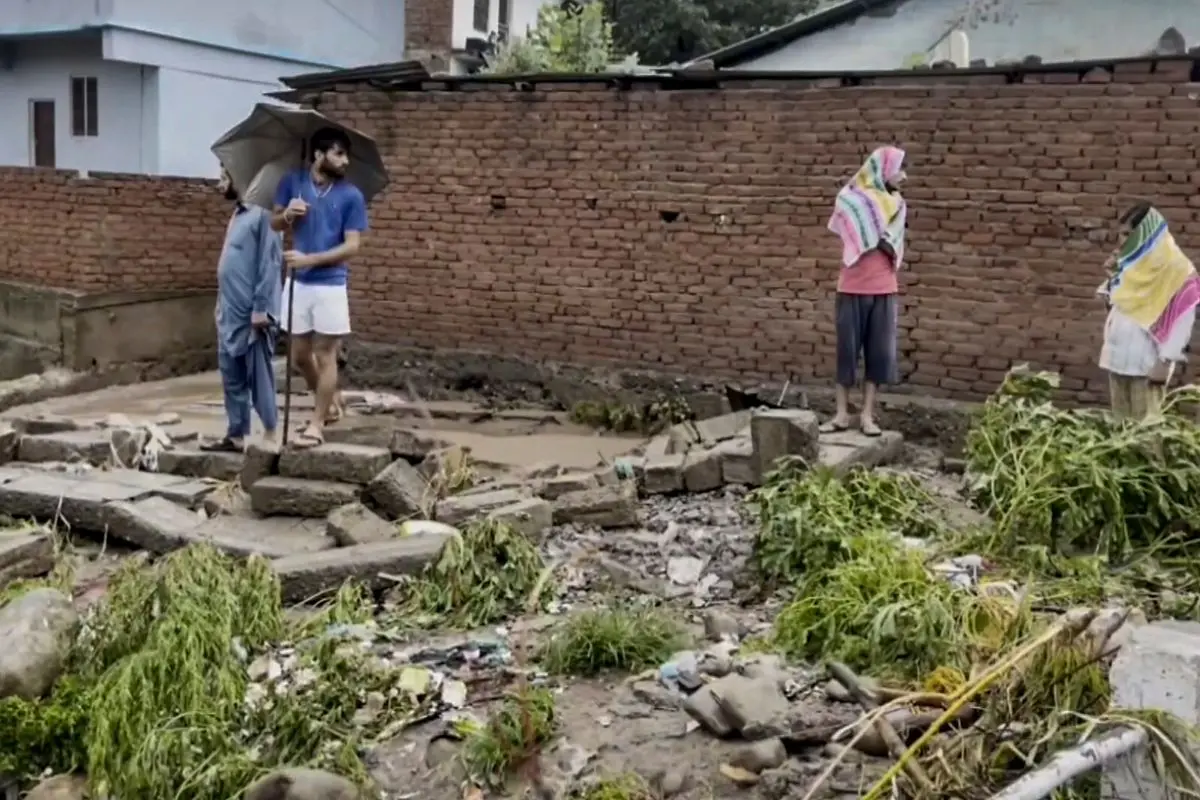 People stand amid debris after flash floods caused by incessant overnight rainfall in Mendhar, Poonch district, Jammu and Kashmir, Sunday, July 19, 2026. (PTI Photo)