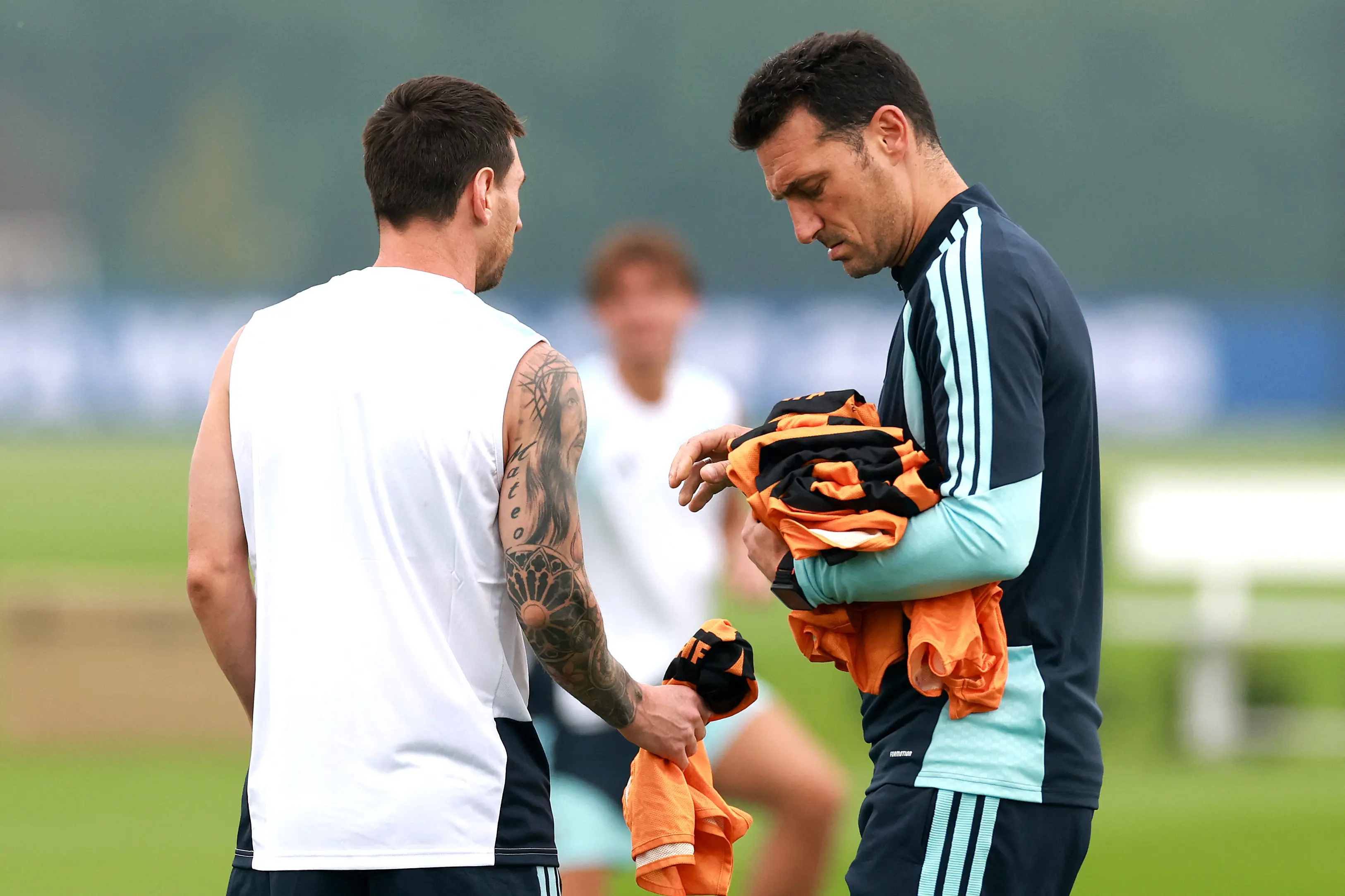 Lionel Scaloni, Head Coach of Argentina, hands in bibs to Lionel Messi of Argentina during a training session | Getty Images via AFP