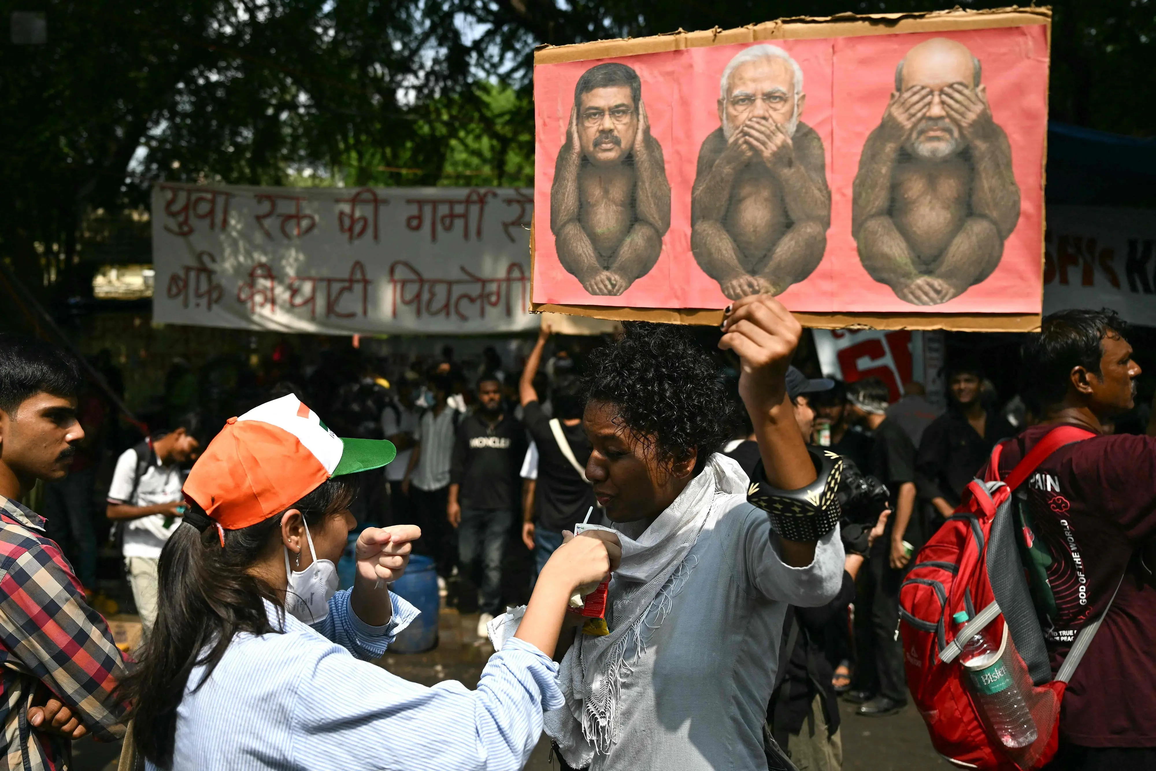 A Cockroach Janta Party (CJP) supporter holds a placard as she drinks ORS, at Jantar Mantar in New Delhi on July 23, 2026 during the ongoing protest to demand the resignation of India's Education Minister Dharmendra Pradhan over alleged NEET exam irregularities. Indian Prime Minister Narendra Modi on July 23 vowed "stringent punishment" for those involved in exam fraud that has fuelled student anger, in his first direct comments tied to major protests challenging his government.| Photo: PTI