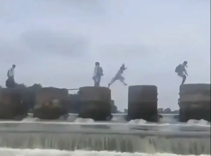 A screengrab of viral video showing students hopping from one pillar after another to cross river