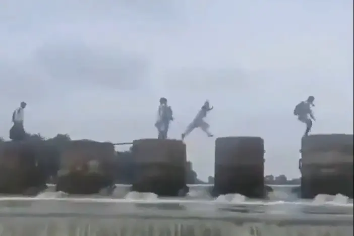 A screengrab of viral video showing students hopping from one pillar after another to cross river