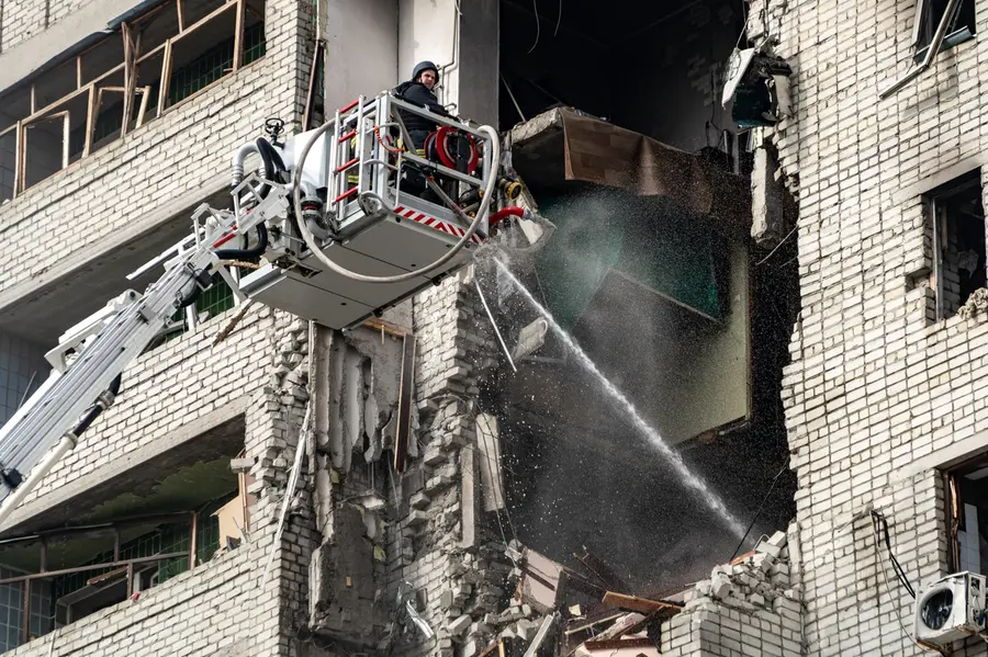 Firefighters put out a fire after a residential building was hit following Russia's drone attack in Kharkiv