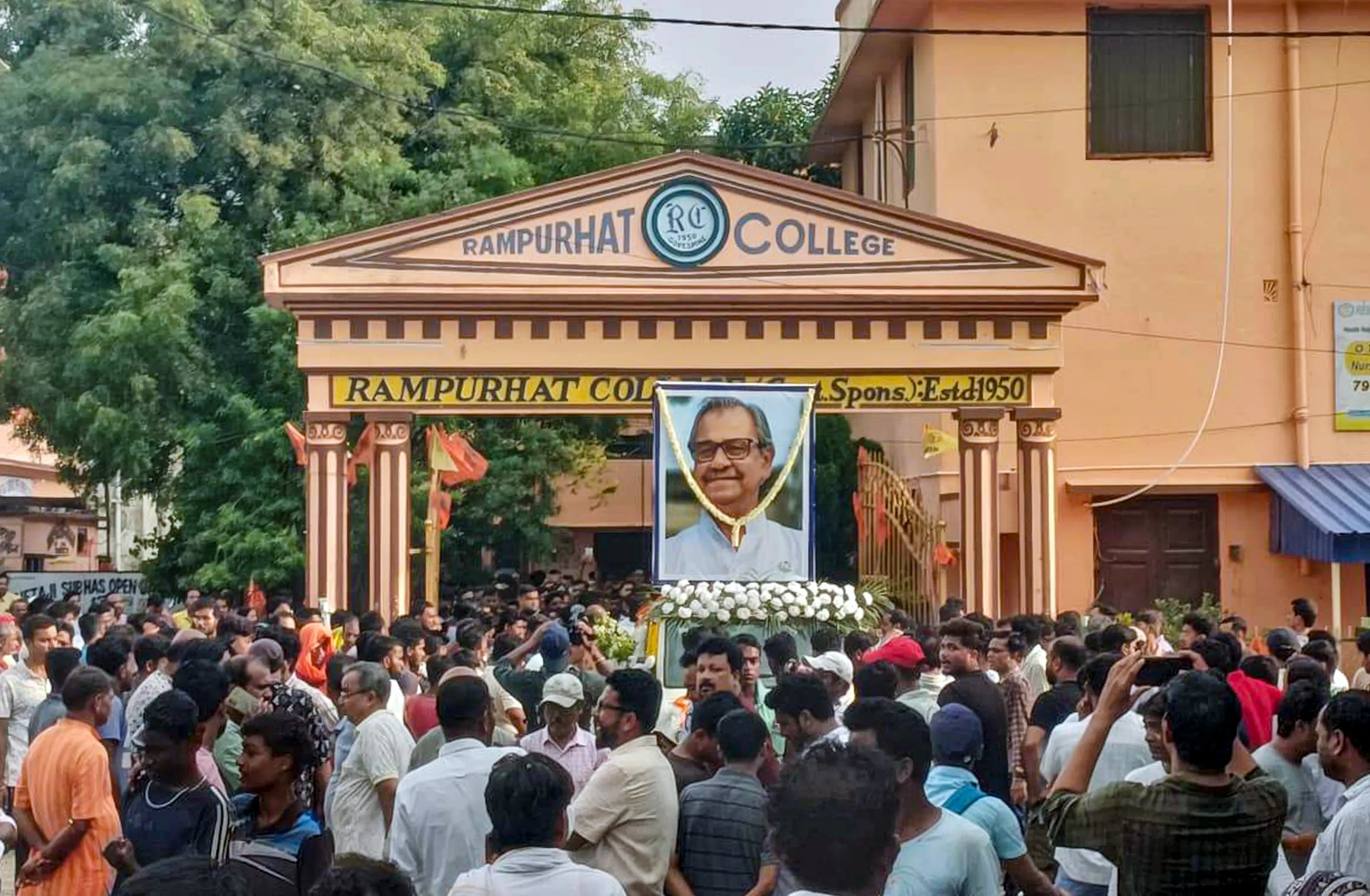 People gather as mortal remains of former West Bengal Assembly deputy speaker and TMC leader Ashis Banerjee are being taken for his last rites, at Rampurhat College, in Birbhum district.| Photo: PTI
