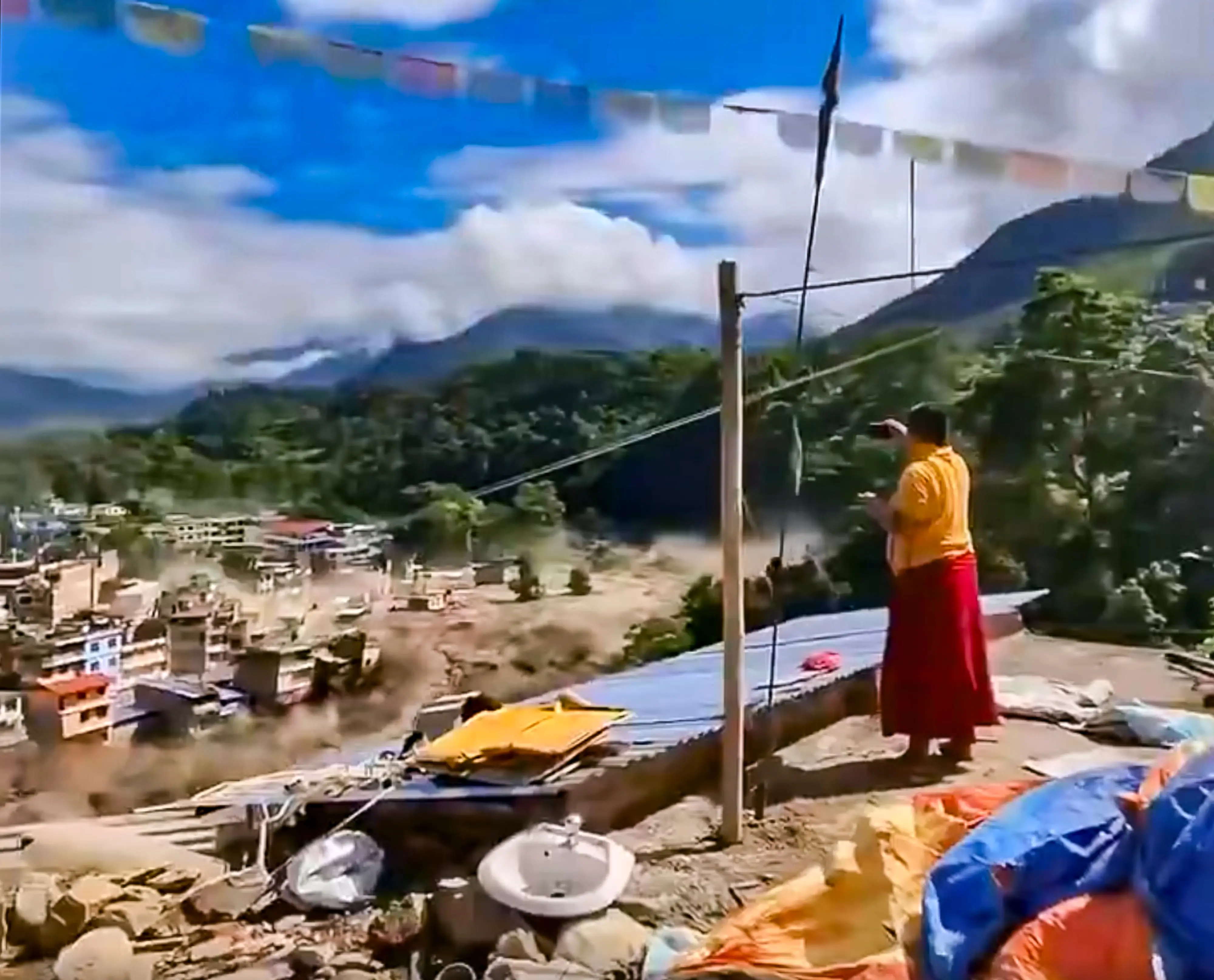 A woman looks on as the floodwater flows in spate across a residential area in Nepal | PTI
