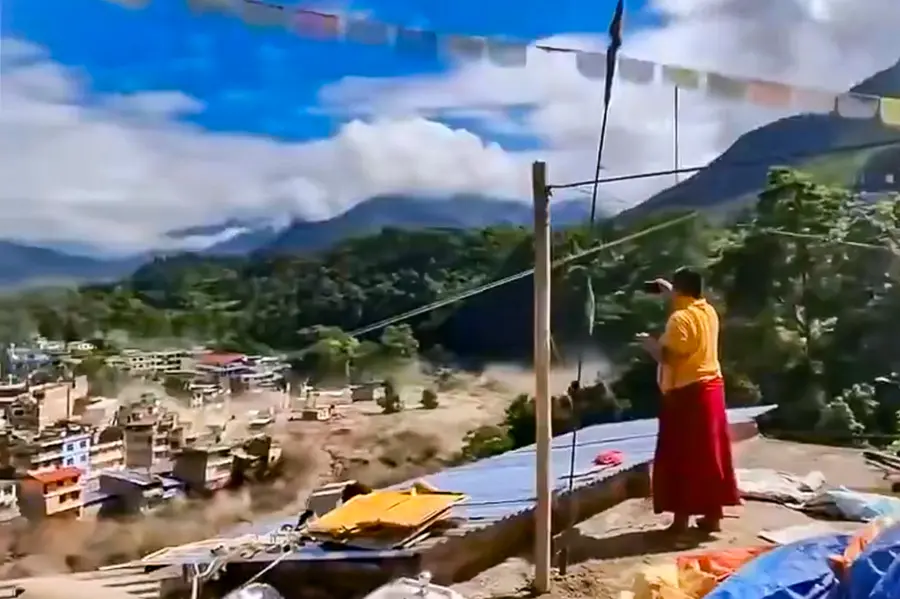 A woman looks on as the floodwater flows in spate across a residential area in Nepal