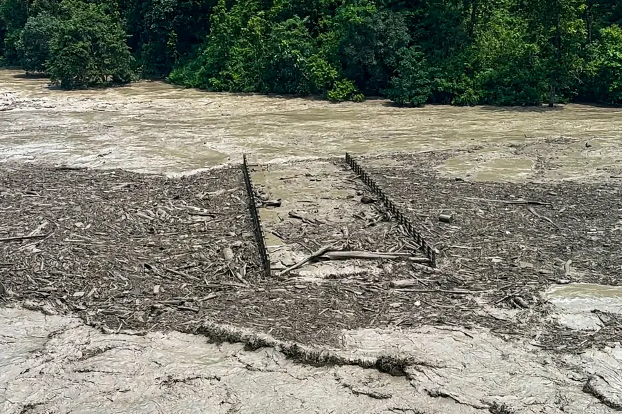 A view of massive debris and thick mud completely submerging a suspension bridge following the flash floods at Beni Ghat area