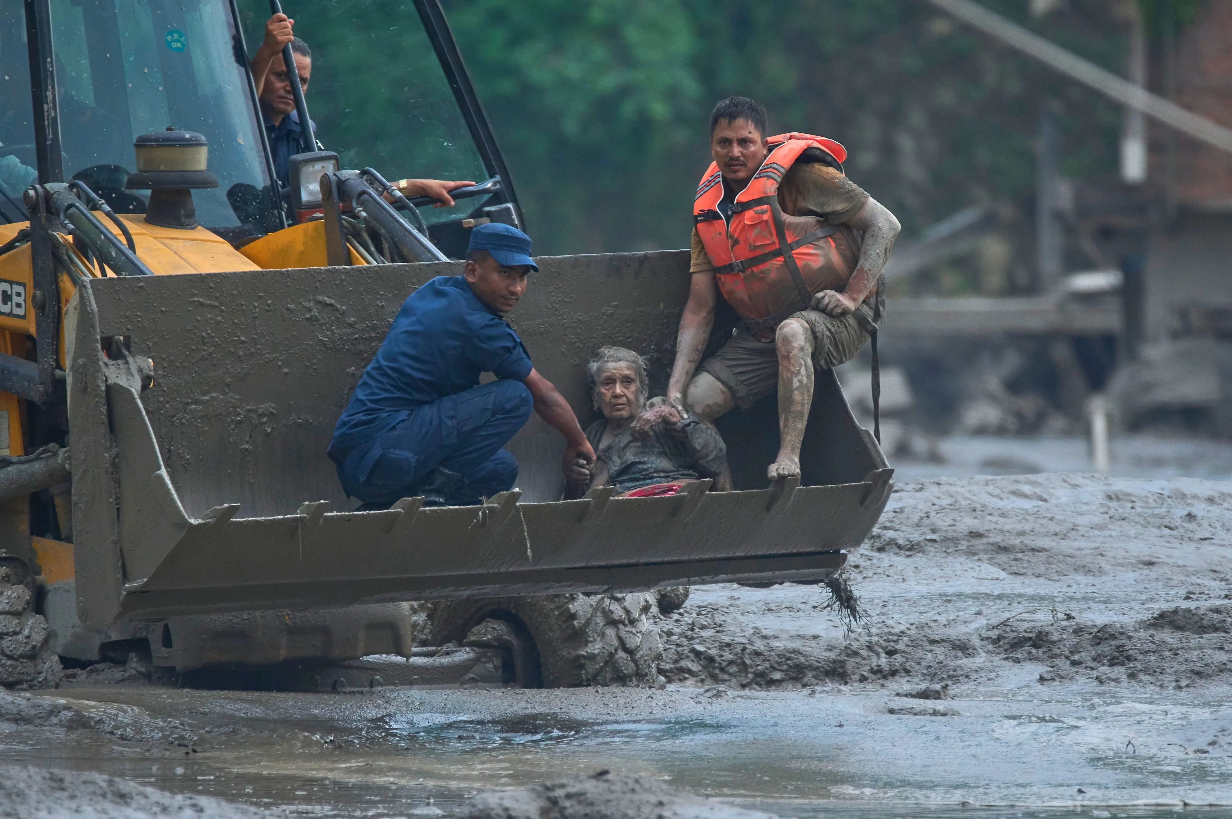 Rescuers use an earthmover to carry a victim of flash flooding to safety along the Trishuli River in Nepal's Nuwakot district