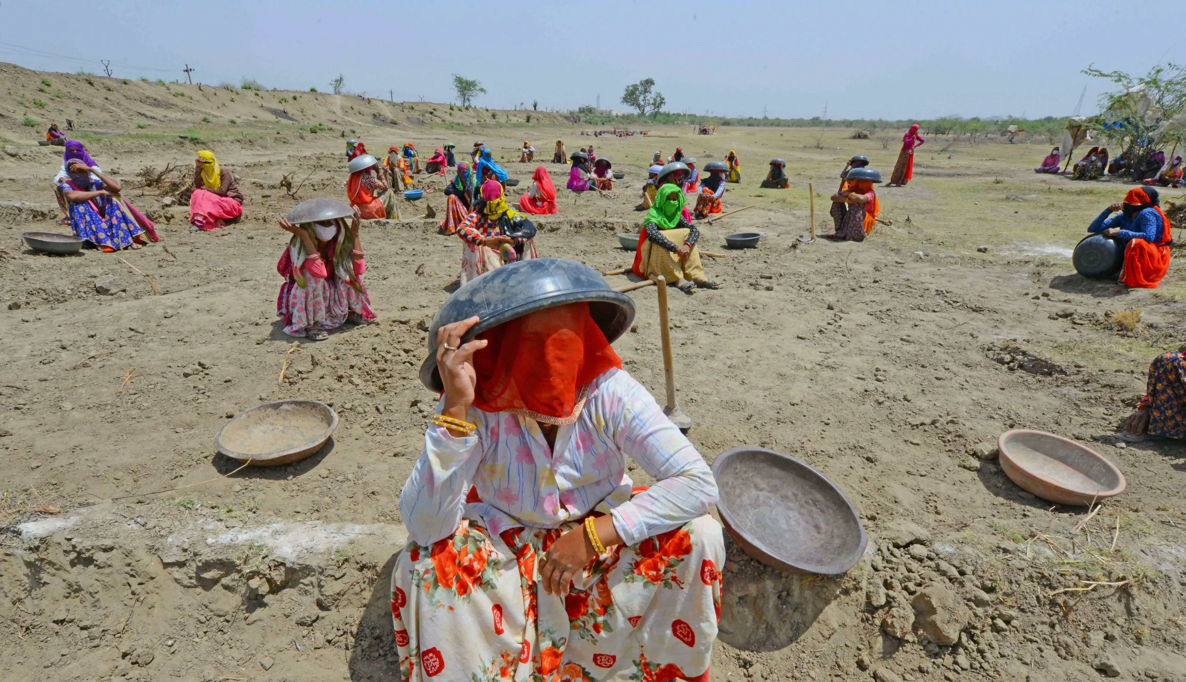 Labourers under Mahatma Gandhi National Rural Employment Guarantee Act (MNREGA) sit under tagaris (a pan to carry loads like soil) to protect themselves against the scorching sun, as they work at a site during ongoing COVID-19 lockdown, on the outskirts of Beawar.| File iamge: PTI