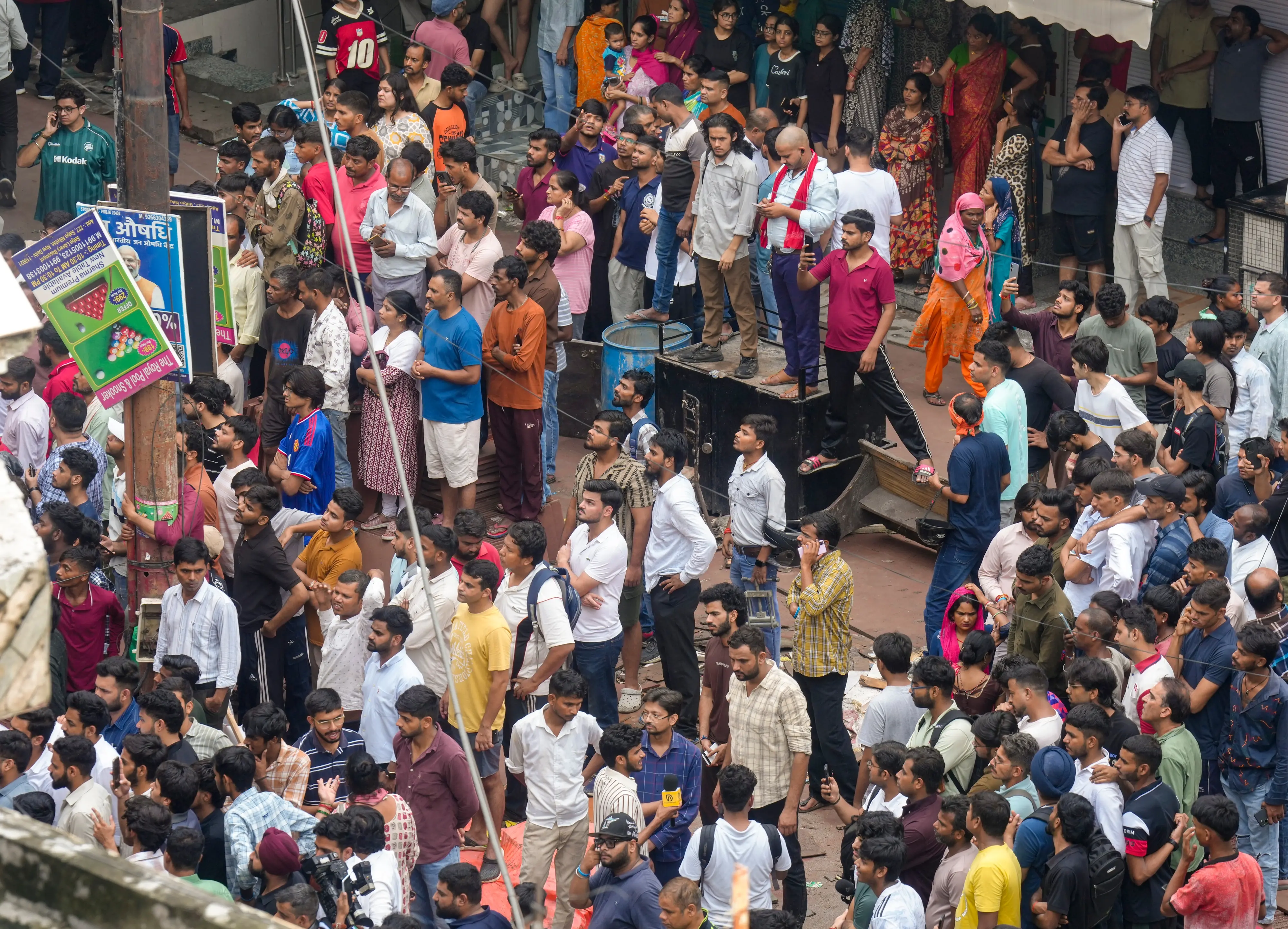 Neighbours look on during a rescue operation after a 50-year-old five-storey building housing a boys' hostel collapsed in a congested bylane in Satya Niketan