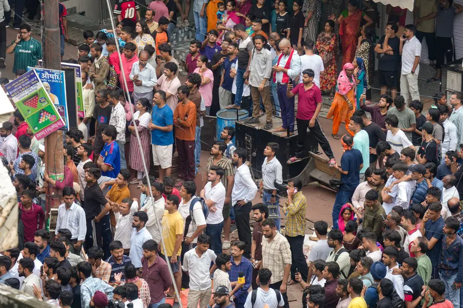Neighbours look on during a rescue operation after a 50-year-old five-storey building housing a boys' hostel collapsed in a congested bylane in Satya Niketan
