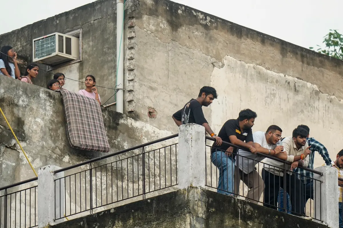 Neighbours look on during a rescue operation after a 50-year-old five-storey building housing a boys' hostel collapsed in a congested bylane in Satya Niketan near Delhi University's south campus | Photo: PTI