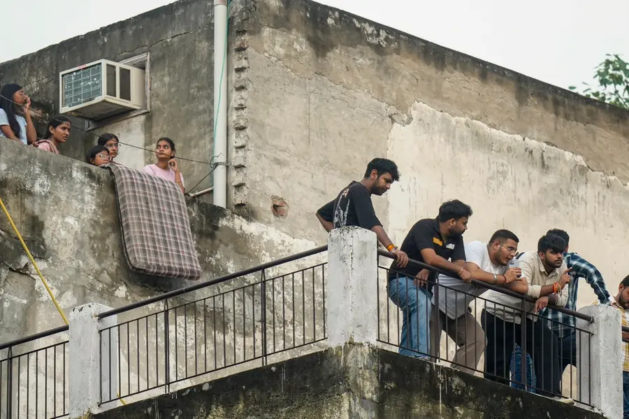 Neighbours look on during a rescue operation after a 50-year-old five-storey building housing a boys' hostel collapsed in a congested bylane in Satya Niketan near Delhi University’s south campus
