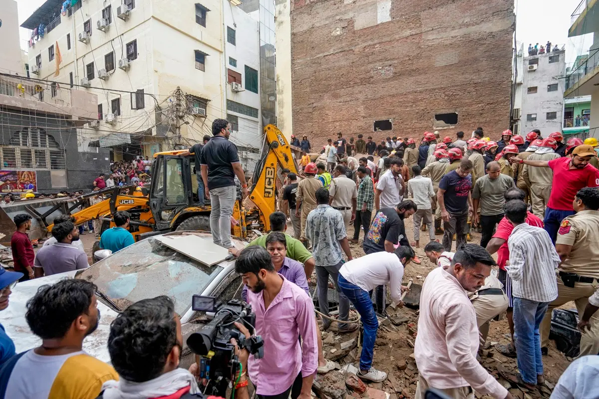 People gather on site after a five-storey building collapsed at Satya Niketan area | Photo: PTI