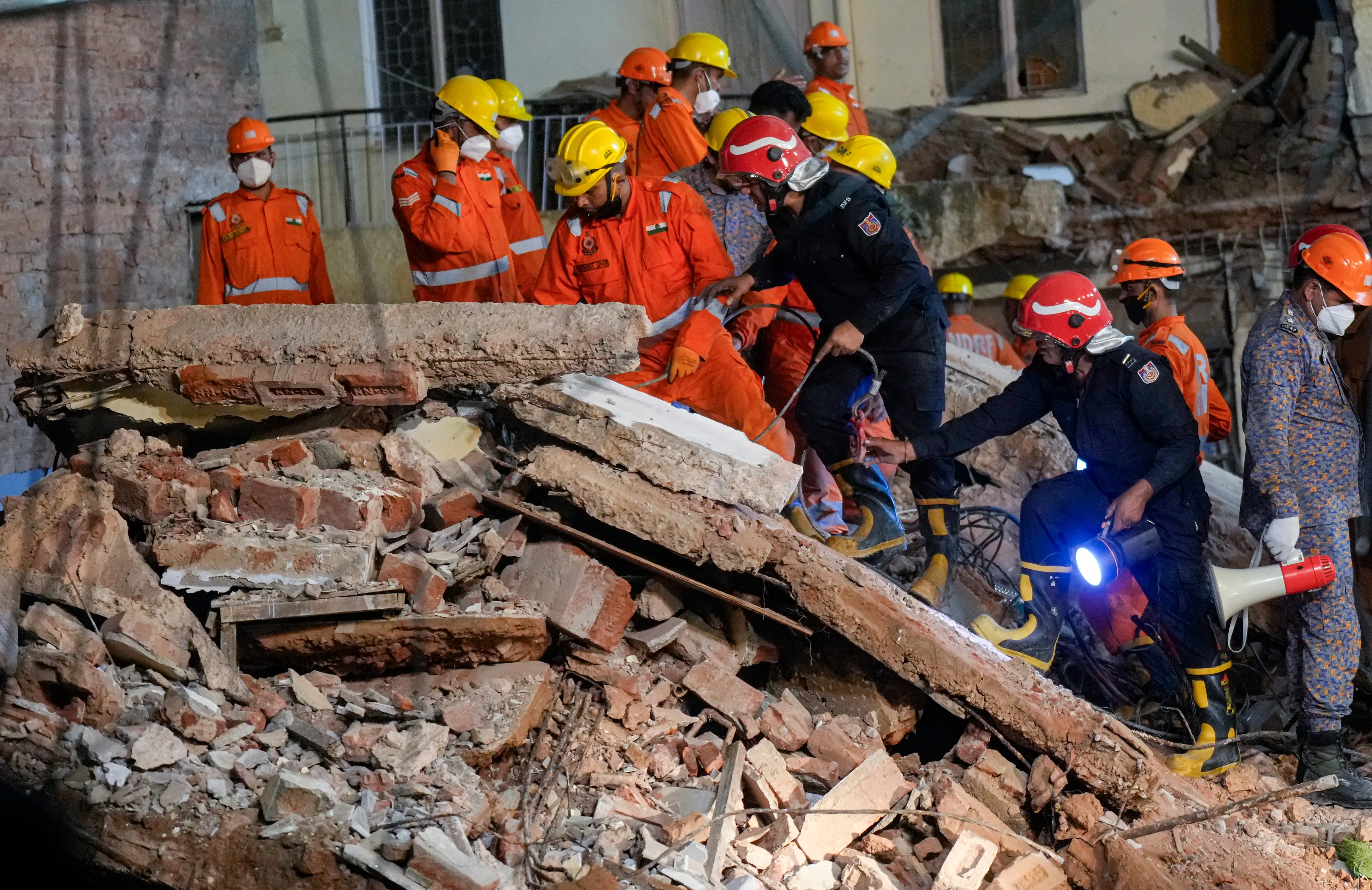 NDRF, fire department officials during a rescue operation after a 50-year-old five-storey building housing a boys' hostel collapsed in a congested bylane in Satya Niketan near Delhi University's south campus | Photo: PTI