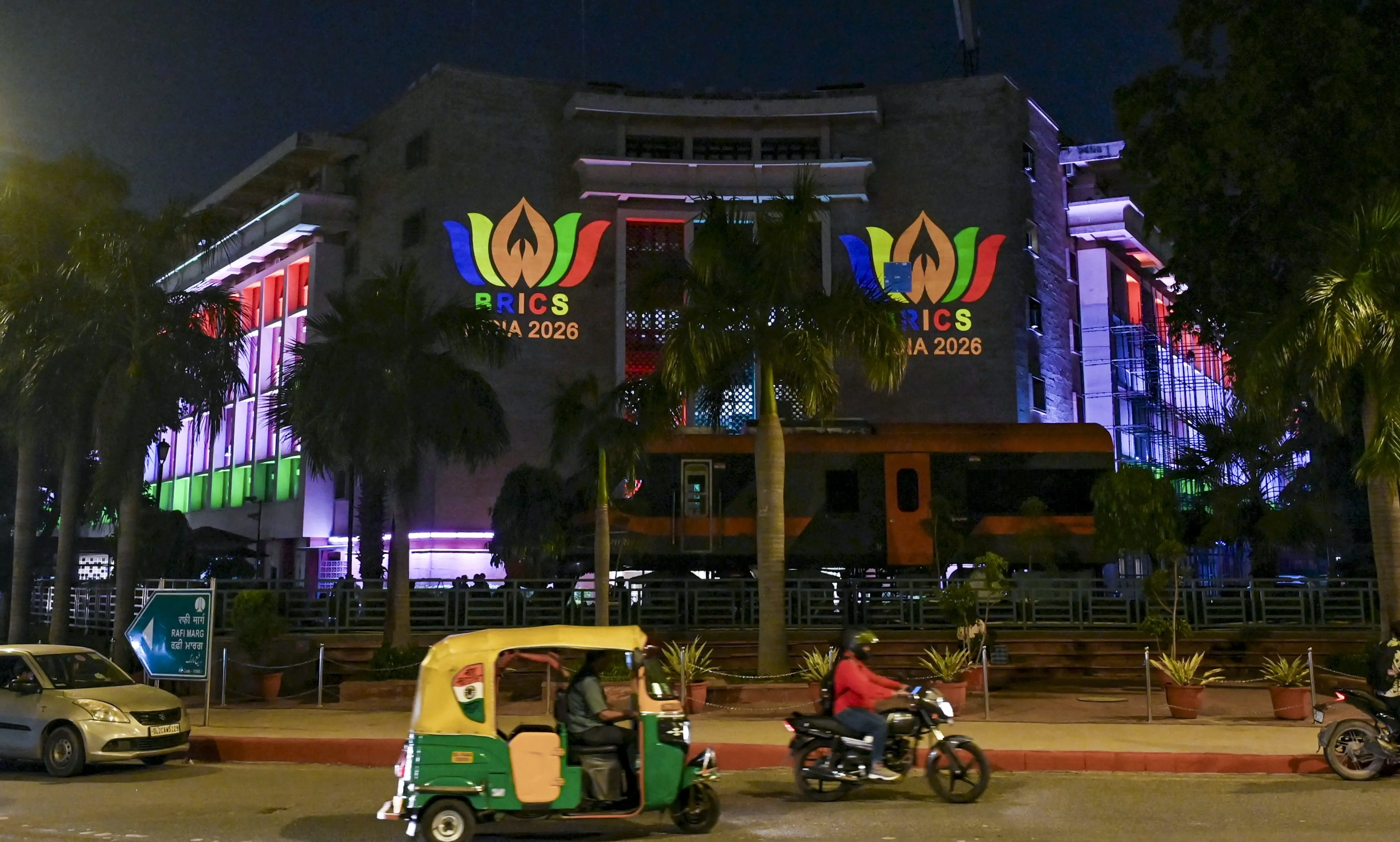 Vehicles move on a road near the Rail Bhavan, illuminated with decorative lighting and projection displays ahead of the 18th BRICS Summit 2026, in New Delhi.| Photo: PTI