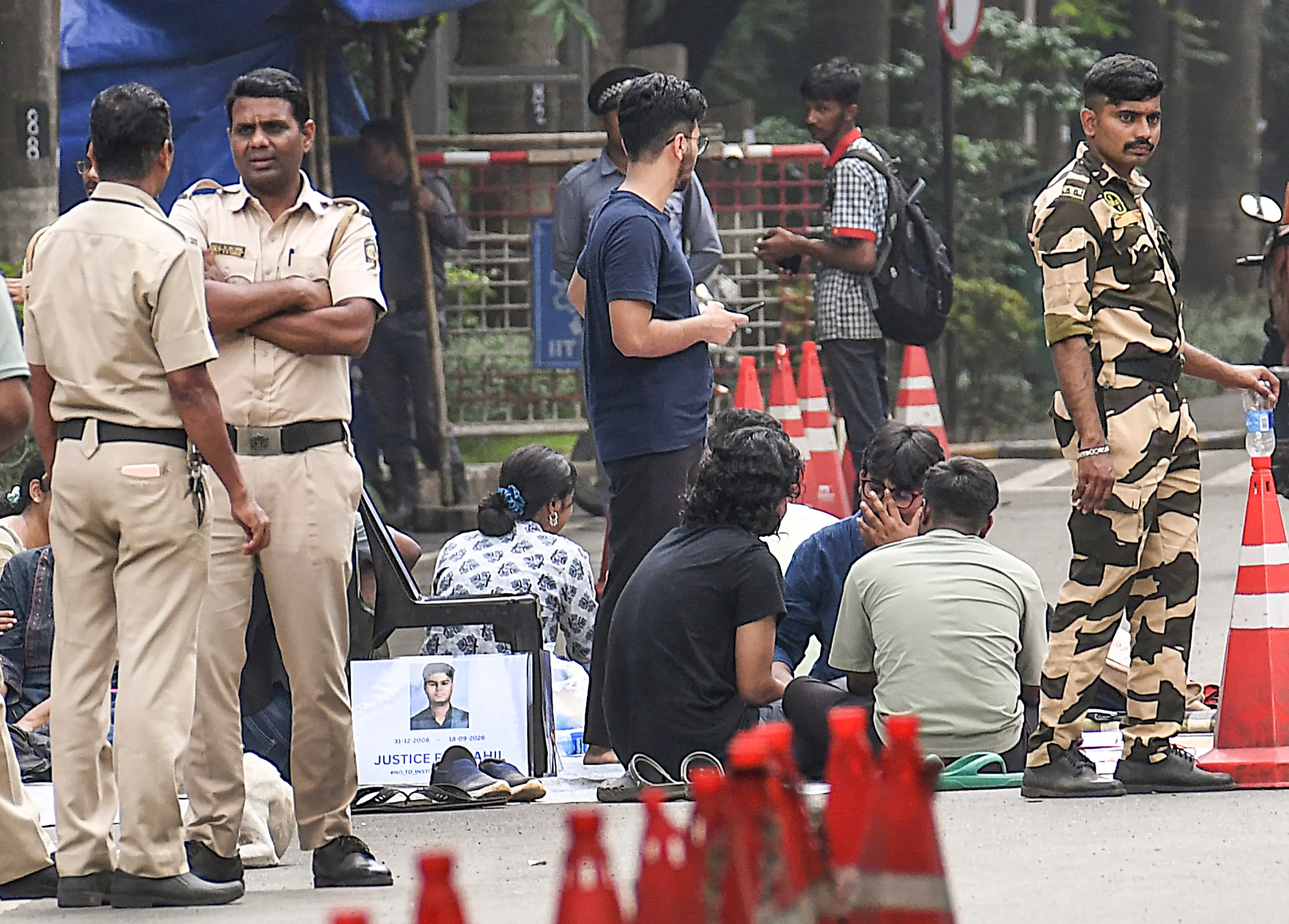ecurity personnel stand guard as students stage a protest following the death of a 22-year-old Indian Institute of Technology (IIT) Bombay student, who died by suicide in his hostel room after he was allegedly caught using a mobile phone during an examination, at IIT Bombay, in Mumbai, Maharashtra.| Photo: PTI