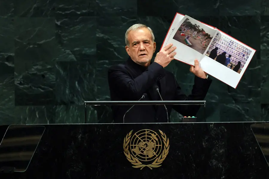 Iranian President Masoud Pezeshkian holds up a picture of supposed victims killed during the Israeli and American airstrikes