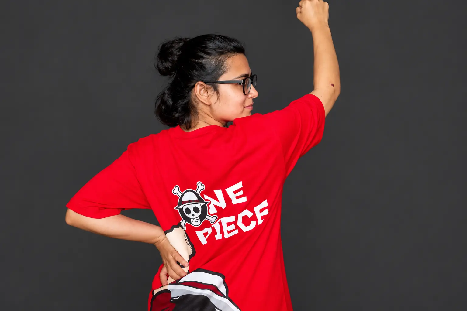 AISA national president Neha Bora raises her fist during the Jantar Mantar protest in New Delhi, wearing a red One Piece T-shirt featuring the Straw Hat Pirates' flag, a symbol increasingly associated with Gen Z-led resistance movements.