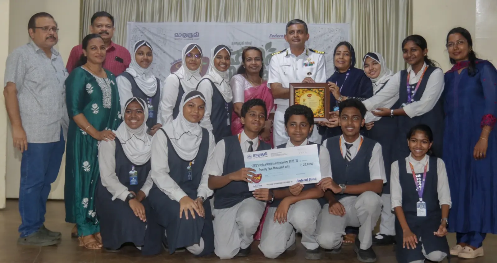SEED students and teachers from Karumalloor Alangad Jama-ath Public School receive the District Sreshtha Haritha Vidyalayam Award under the Mathrubhumi SEED project from Captain Manoj Kumar, Officer-in-Charge, Naval Construction Wing, Southern Naval Command. Also present are Lakshmisree (Deputy Director, Agriculture Department), S. Prakash (Senior News Editor, Mathrubhumi), and S. Manoj Kumar (Senior Circulation Manager).