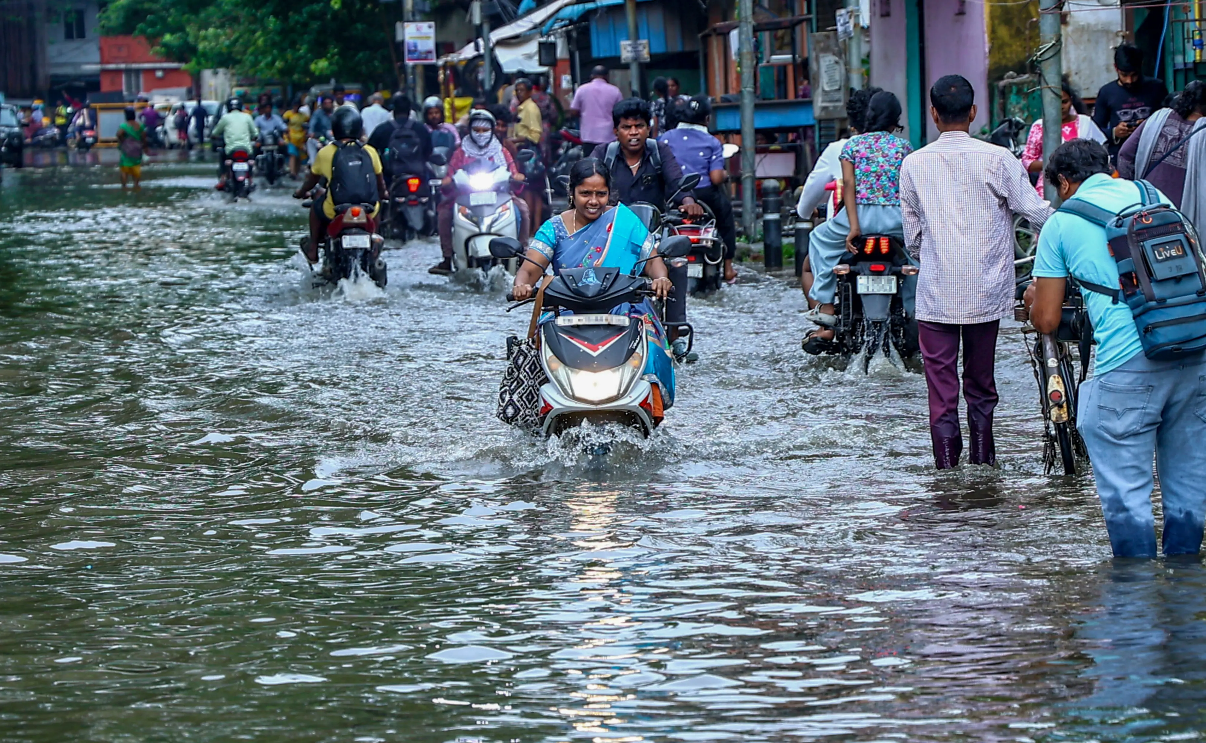 Commuters wade through a waterlogged street following heavy rain in Chennai on Sunday, Oct 18, 2026 | Photo: PTI