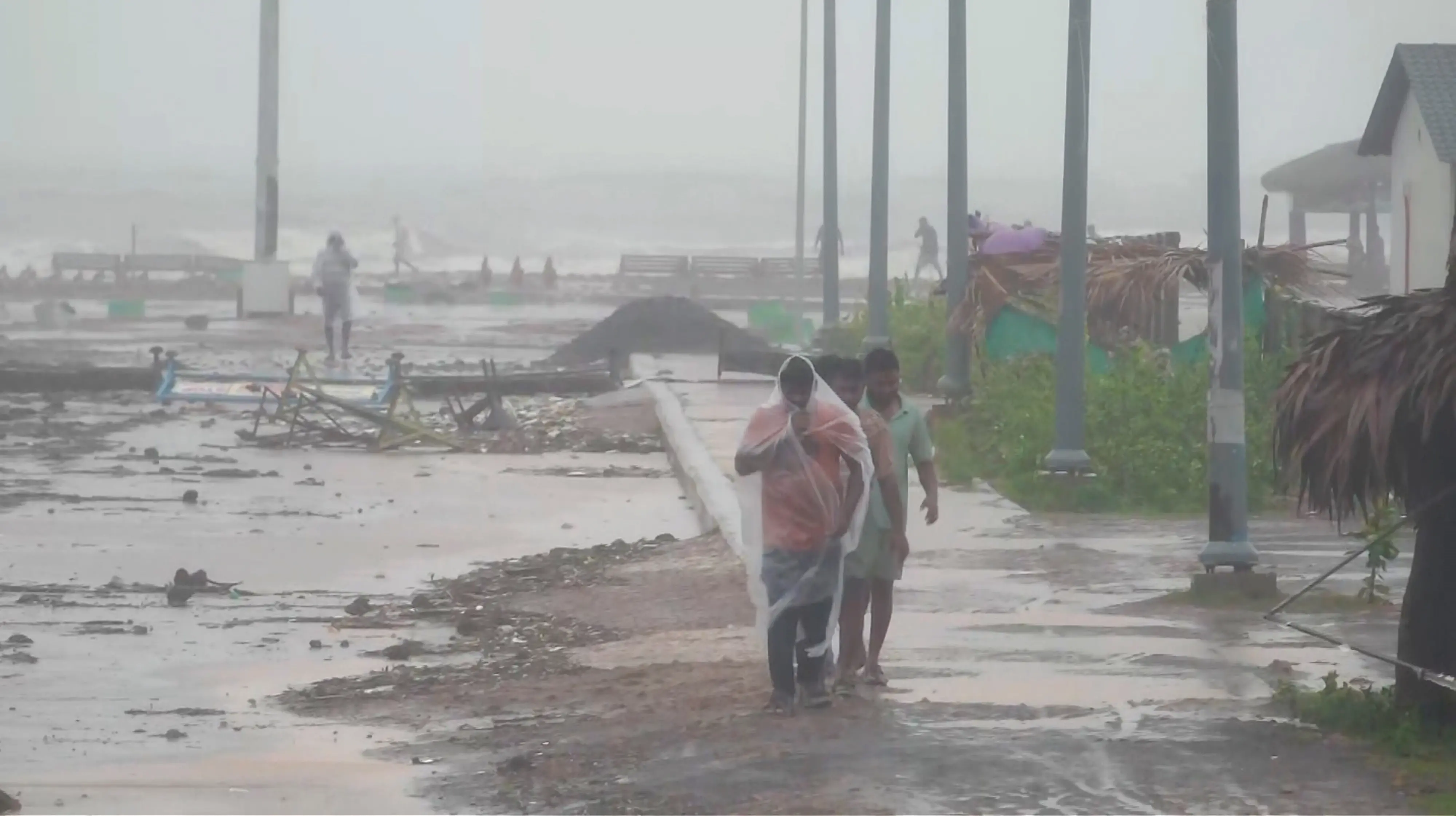 People walk amid strong winds and rainfall at a coastal area during Cyclone Arnab's landfall, in Kakinada, Andhra Pradesh, on Wednesday | Photo: PTI